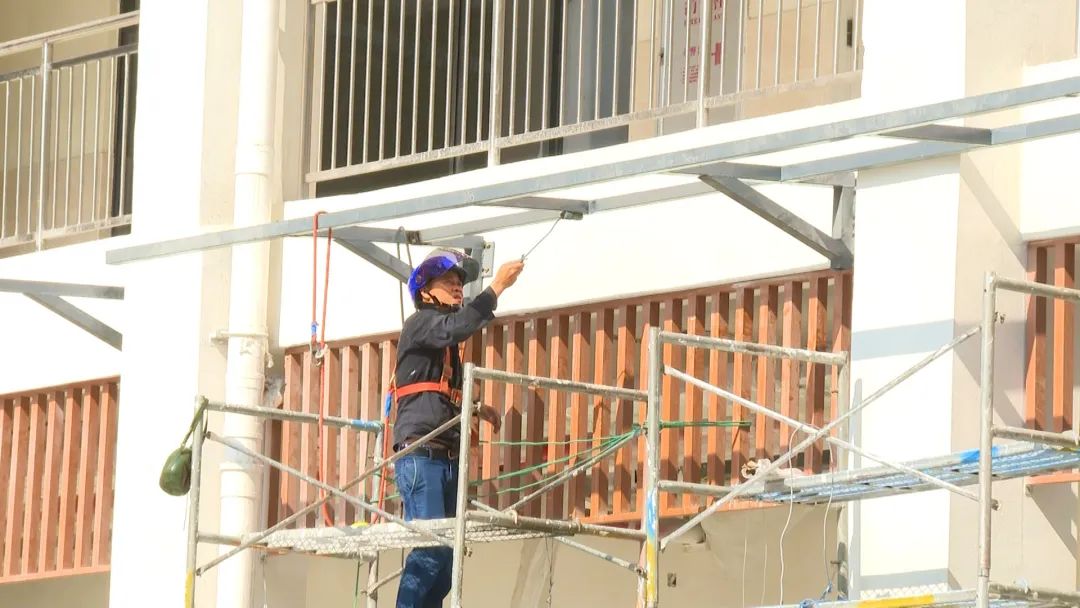 图为工人正在为大楼外部建筑刷漆。