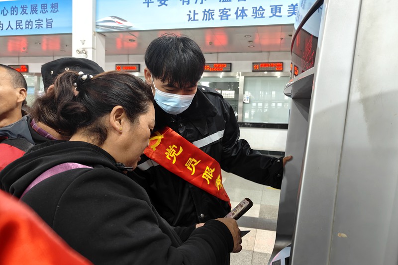 在海口站，志愿者帮助旅客购票。唐璐璐摄