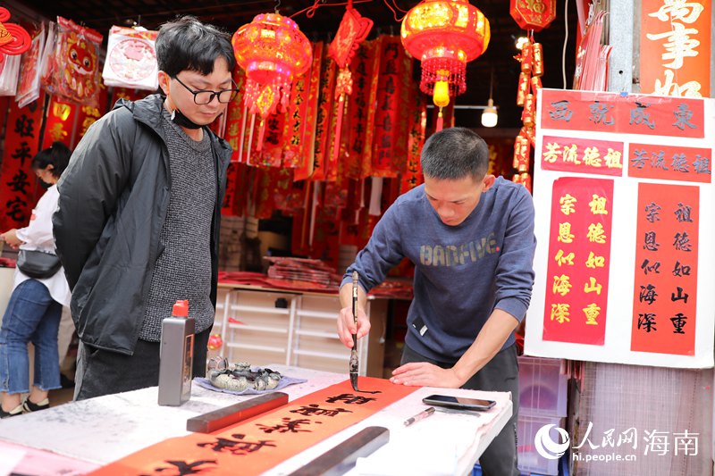 店铺老板为购买春联的顾客现场写一副春联。 人民网记者 孟凡盛摄