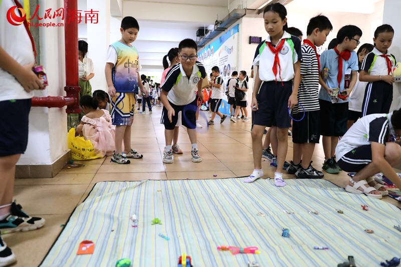 5月31日，在海口市第二十五小学公益跳蚤市场上，学生通过做游戏来赢得喜爱的物品。 人民网记者 孟凡盛摄