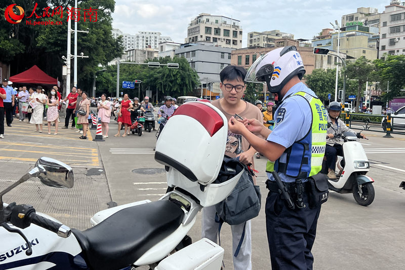 在海南省农垦中学考点，交警载着考生取回身份证后返回考点。 人民网记者 李学山摄