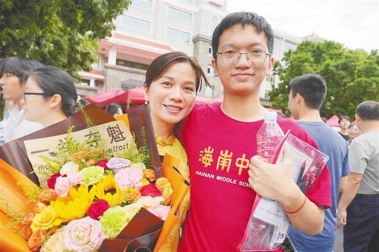 在海南中学高中部考点，一位考生家长拿着鲜花迎接完成高考的孩子。