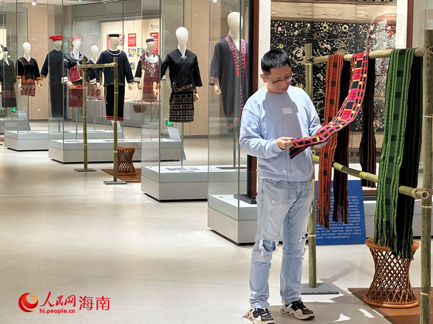 观众在“黎华锦簇——黎族传统纺染织绣技艺保护成就展”亲手触摸黎锦的质感。人民网 刘杨摄
