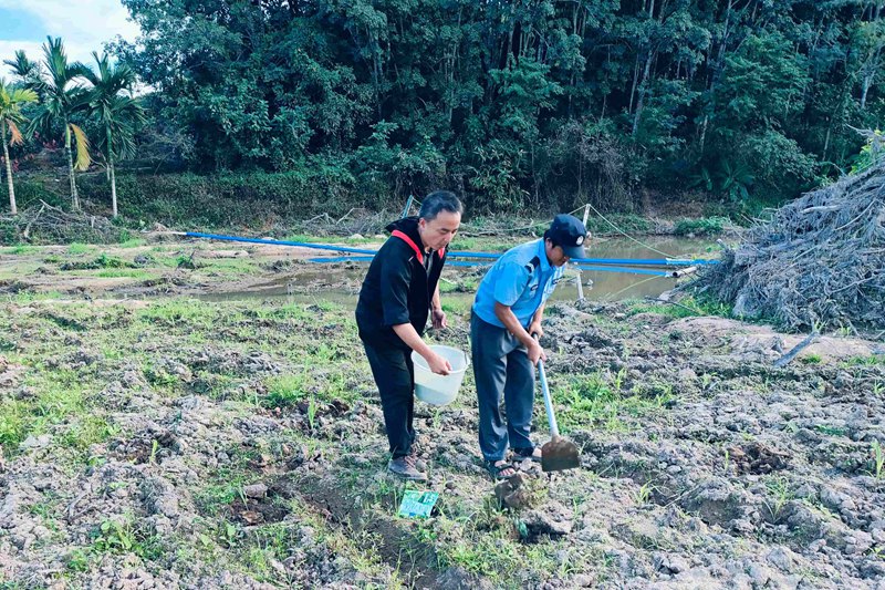 范平钊（左一）帮助农户锄地。育才生态区马脚村委会供图.jpg