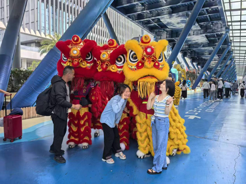 在三亚凤凰国际机场,游客与舞狮互动。海南省旅文厅供图