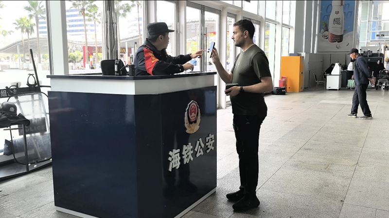 执勤民警为外籍乘客核对相关信息。海口东站派出所供图