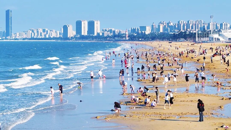 滨海踏浪休闲人潮。海口旅文局供图