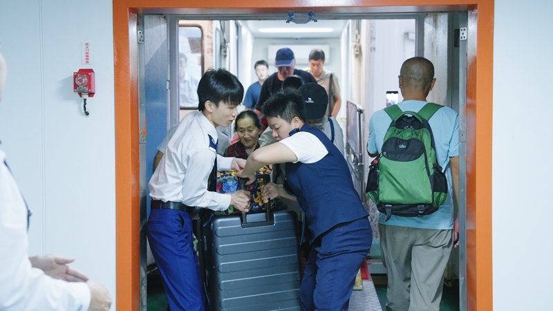 乘务员帮助旅客抬大件行李。海峡股份供图
