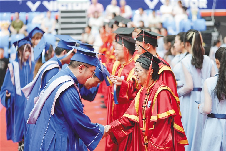 海南大学毕业生们身着学士服，依次接受拨穗礼。