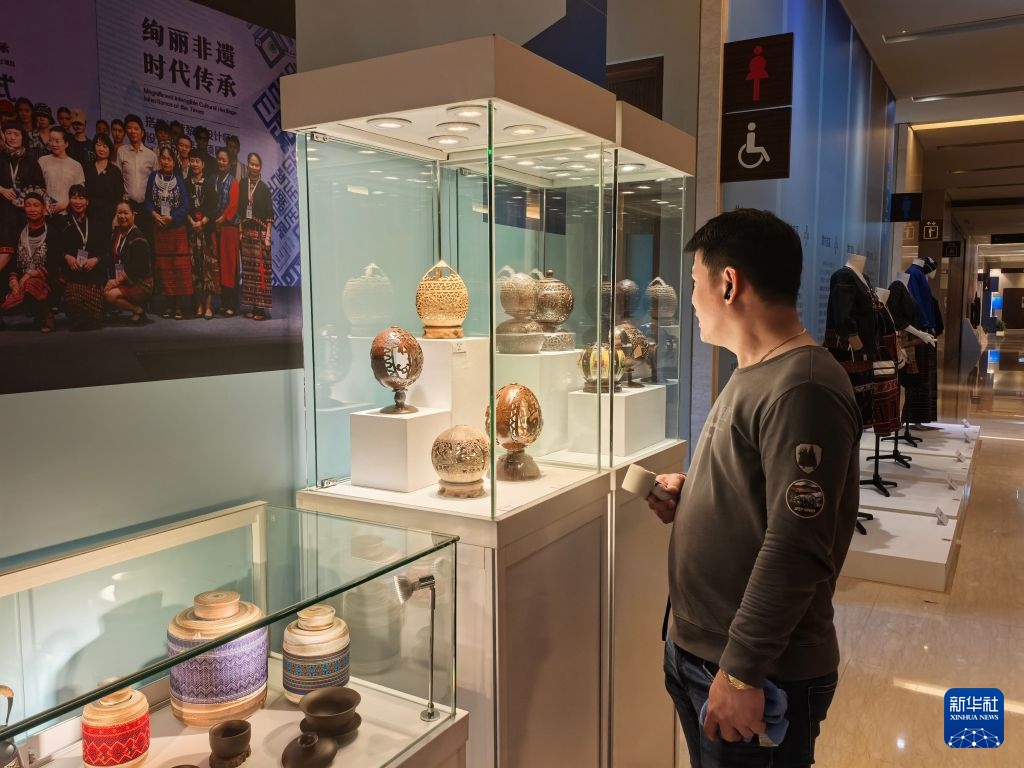 10月3日，菲律宾游客在海南非物质文化遗产主题展上参观椰雕展品。新华社记者 马欣然 摄
